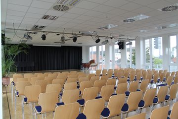 Saal des Kulturhauses Ibbenbüren mit Bestuhlung vorne und Bühne im Hintergrund