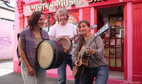 Fragile Matt spielen auf Instrumenten vor einem pinken Laden